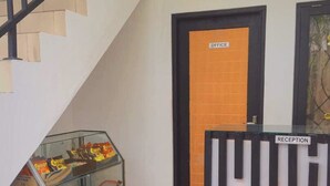 A reception area with a black and white sign, a glass display case with snacks, and a staircase. - Akatara Stay Jimbaran (Jimbaran)