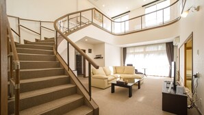 A spacious living area with a curved staircase, a beige sofa, and a coffee table. - Condominium Panoramique Motomachi (Hakodate)