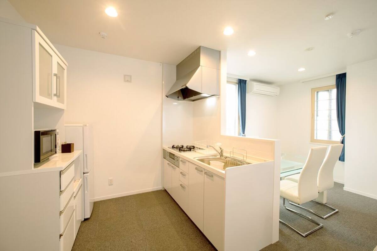 Cocina compacta con armarios blancos, un microondas, una estufa y un lavabo.