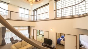 A spacious hotel room with a large window, a sofa, a bed, and a television. - Condominium Panoramique Motomachi (Hakodate)
