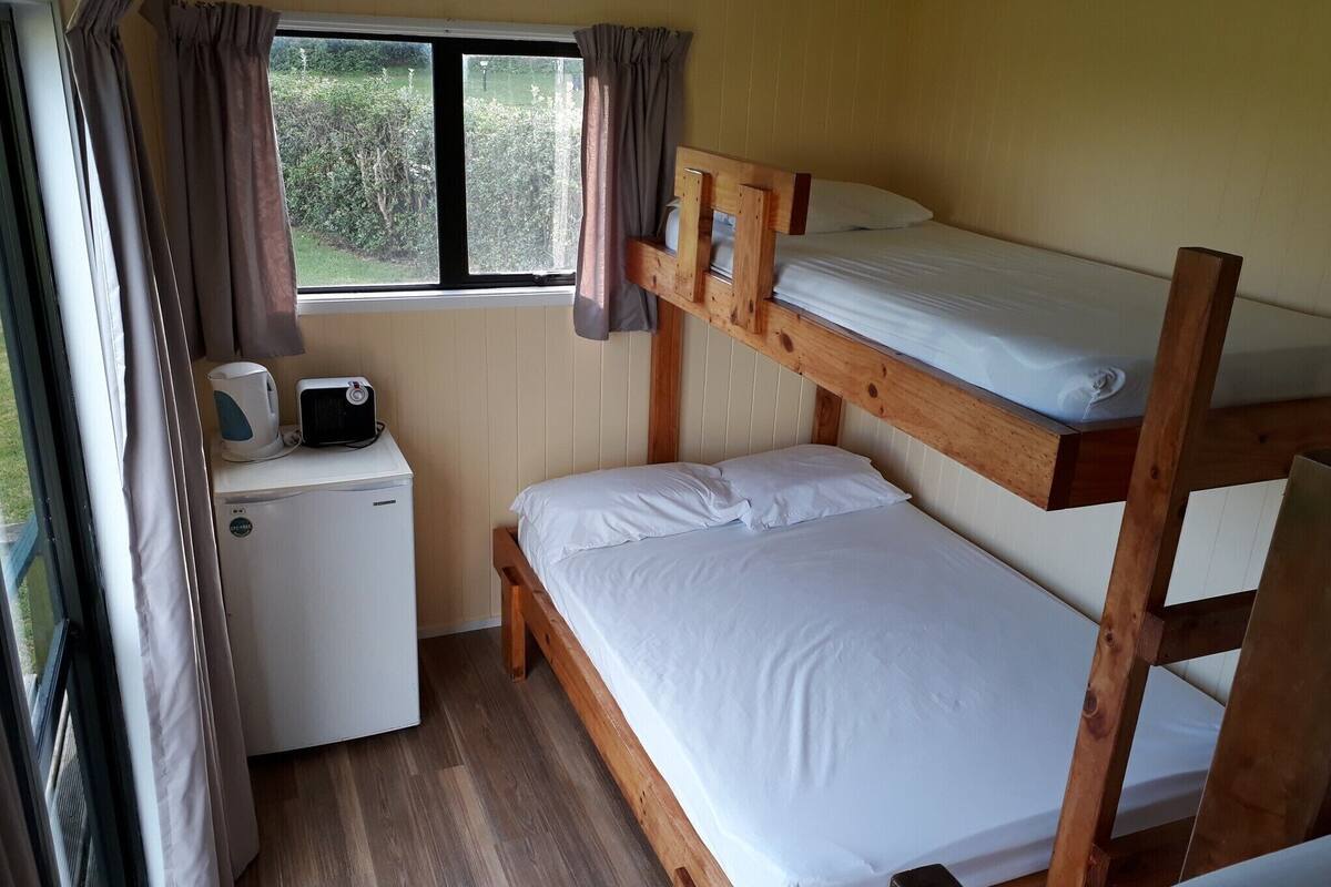 A bunk bed room with a small desk and a window.