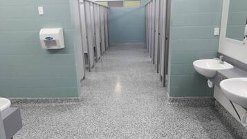 A public restroom with multiple stalls, a hand dryer, and two sinks.