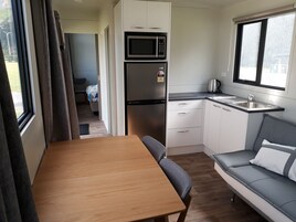 A compact kitchenette with a microwave, refrigerator, and sink.