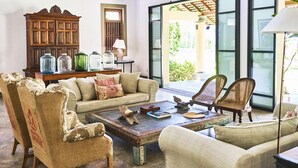 A cozy living room with a sofa, armchairs, a coffee table, and a wooden cabinet with glass jars. - Samadara Estate, Midigama (Ahangama)
