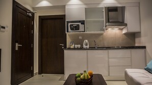 Cocina moderna con microondas, hervidor y lavabo. Hay una cesta de fruta sobre la encimera.