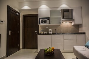 Cocina moderna con microondas, hervidor y lavabo. Hay una cesta de fruta sobre la encimera.