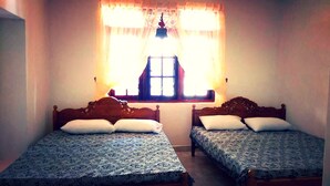 Two single beds with patterned bedding, a window with curtains, and a wooden headboard. - Rockview Holiday Bungalow (Ukuwela)