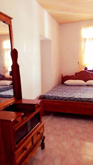 Un dormitorio con un aparador de madera, una cama con ropa de cama estampada y un espejo grande.
