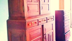 A wooden cabinet with multiple drawers and doors, a dark wooden floor, and a light-colored wall. - Rockview Holiday Bungalow (Ukuwela)