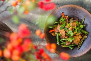 A bowl of food with green beans and meat, served on a rustic brown plate. - No.5 Valley Lodge (Zhangjiajie)
