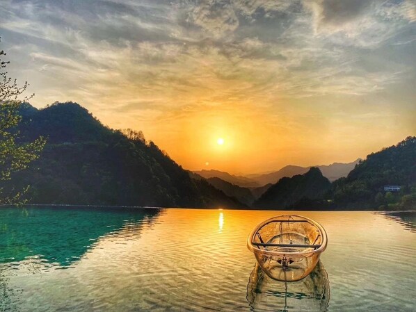 A clear view of a boat on calm water with a sunset in the background. - No.5 Valley Lodge (Zhangjiajie)