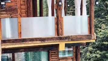 Eine Holzhütte mit Balkon, großen Fenstern und einer Holzterrasse.