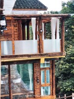 Una cabaña de madera con balcón, ventanas amplias y una terraza de madera.