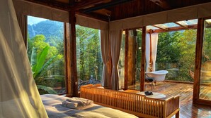 Een slaapkamer met een bed, houten meubels en uitzicht op een natuurlandschap.