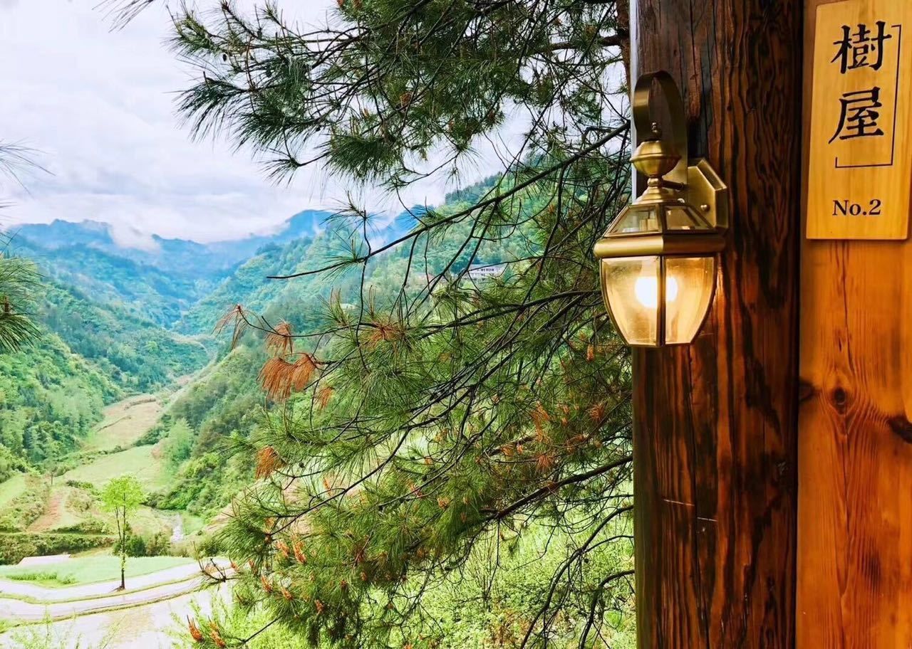 A wooden sign with "No.2" indicating room number, set against a backdrop of a mountainous landscape with pine trees.