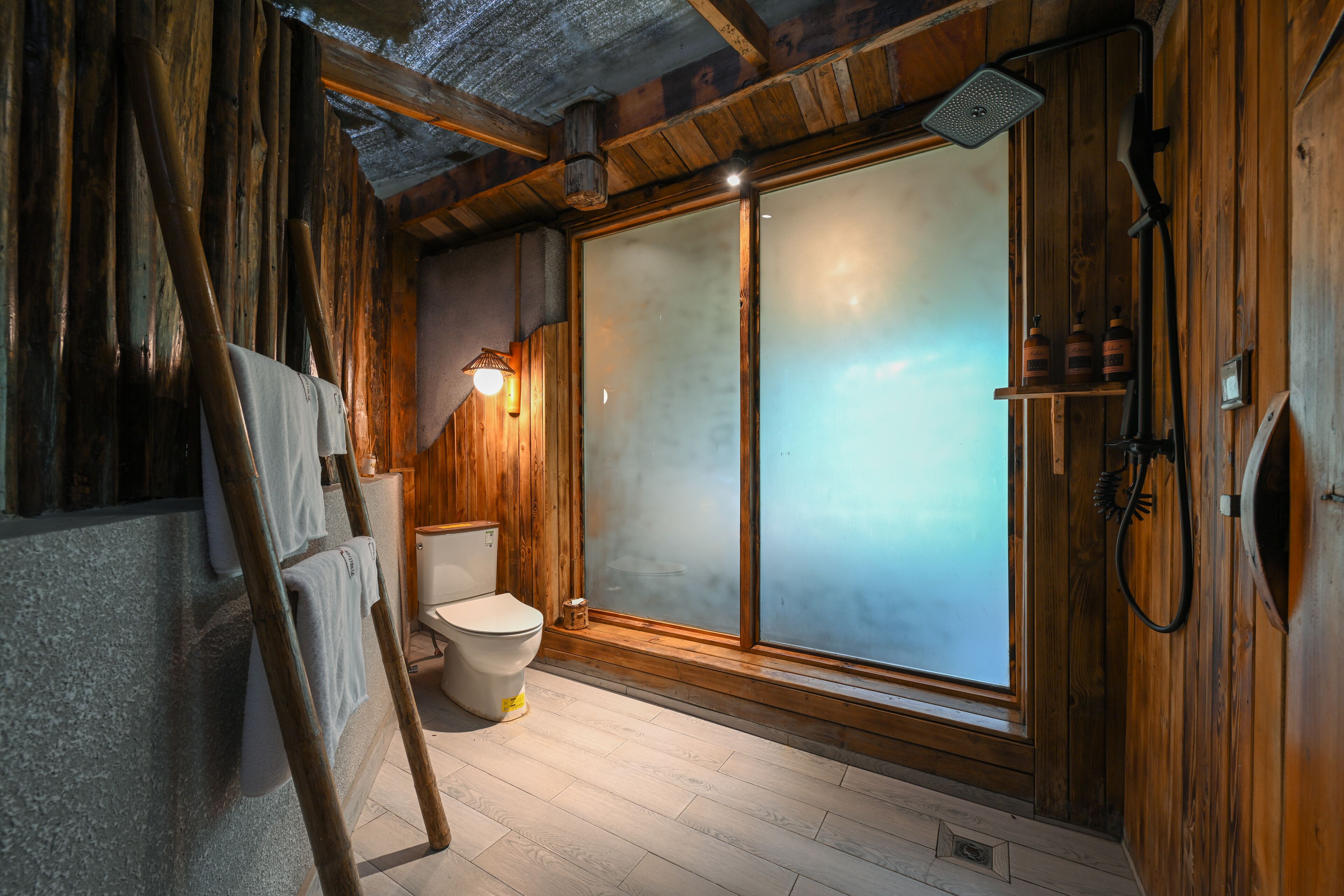A wooden interior with a toilet, a shower, and a large frosted glass door.