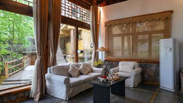 A spacious living area with a sofa, armchairs, and a coffee table. A refrigerator is visible in the corner.