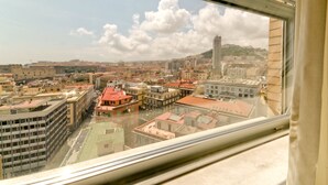Vista urbana desde una ventana, con una mezcla de edificios históricos y modernos, una torre destacada, y cielo despejado con nubes.