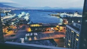 Un paisaje urbano costero al anochecer con vista al mar, barcos y edificios.