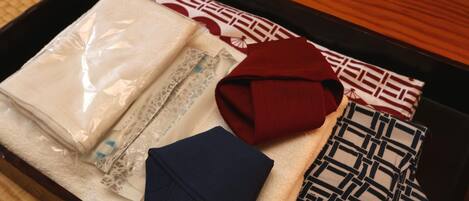 A neatly arranged tray with various textiles, including a folded white fabric, a red garment, a blue piece of clothing, and patterned cushions.