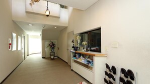 A hallway with a reception desk, a wall-mounted mirror, and a shoe rack.