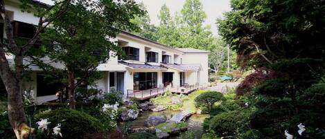 Ein traditionelles japanisches Haus mit Garten, einschließlich eines Koiteichs und verschiedenen Pflanzen.