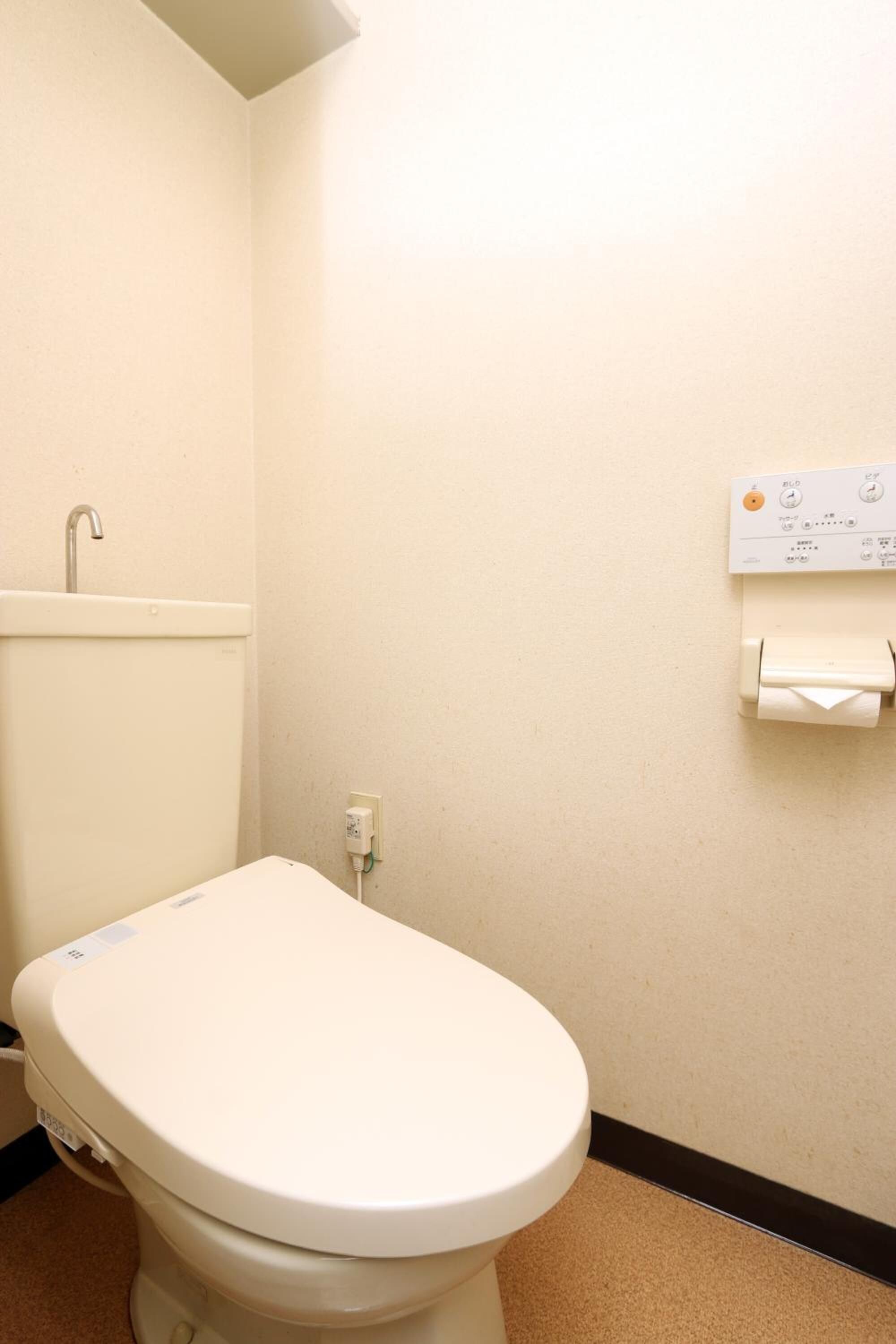 A small, clean bathroom with a toilet, a sink, and a toilet paper holder on the wall.
