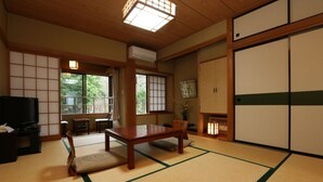 A traditional Japanese room with tatami flooring, a low table, a TV, and sliding doors.