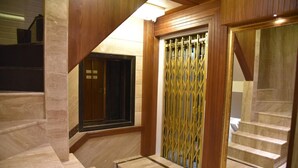 Una escalera con escalones de mármol y paneles de madera que conduce a una habitación con un espejo grande y una reja decorativa.
