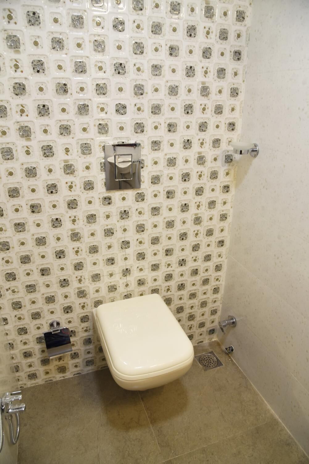 Un baño pequeño con azulejos, un inodoro, una ducha y un perchero de pared.