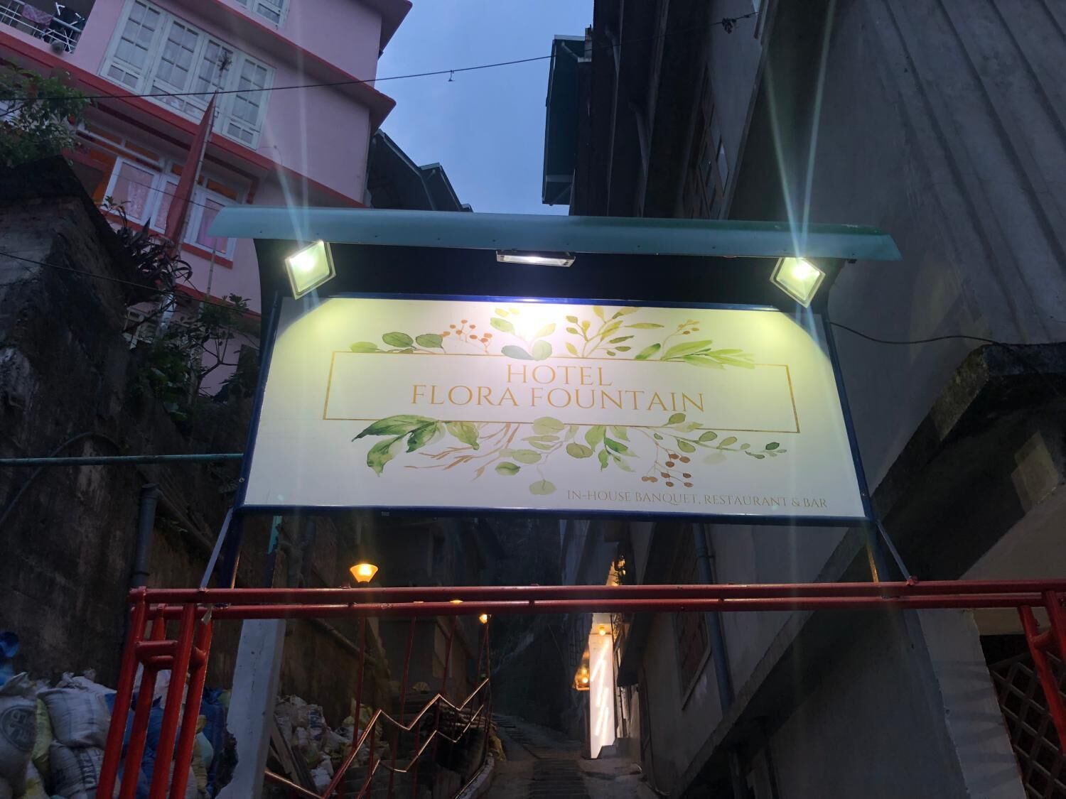 Une enseigne pour l’hôtel Flora Fountain, ornée de motifs floraux, indiquant la présence d’un salon de réception, d’un restaurant et d’un bar.