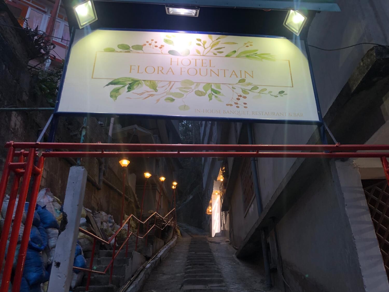 A sign for Hotel Flora Fountain with a staircase leading up to it.