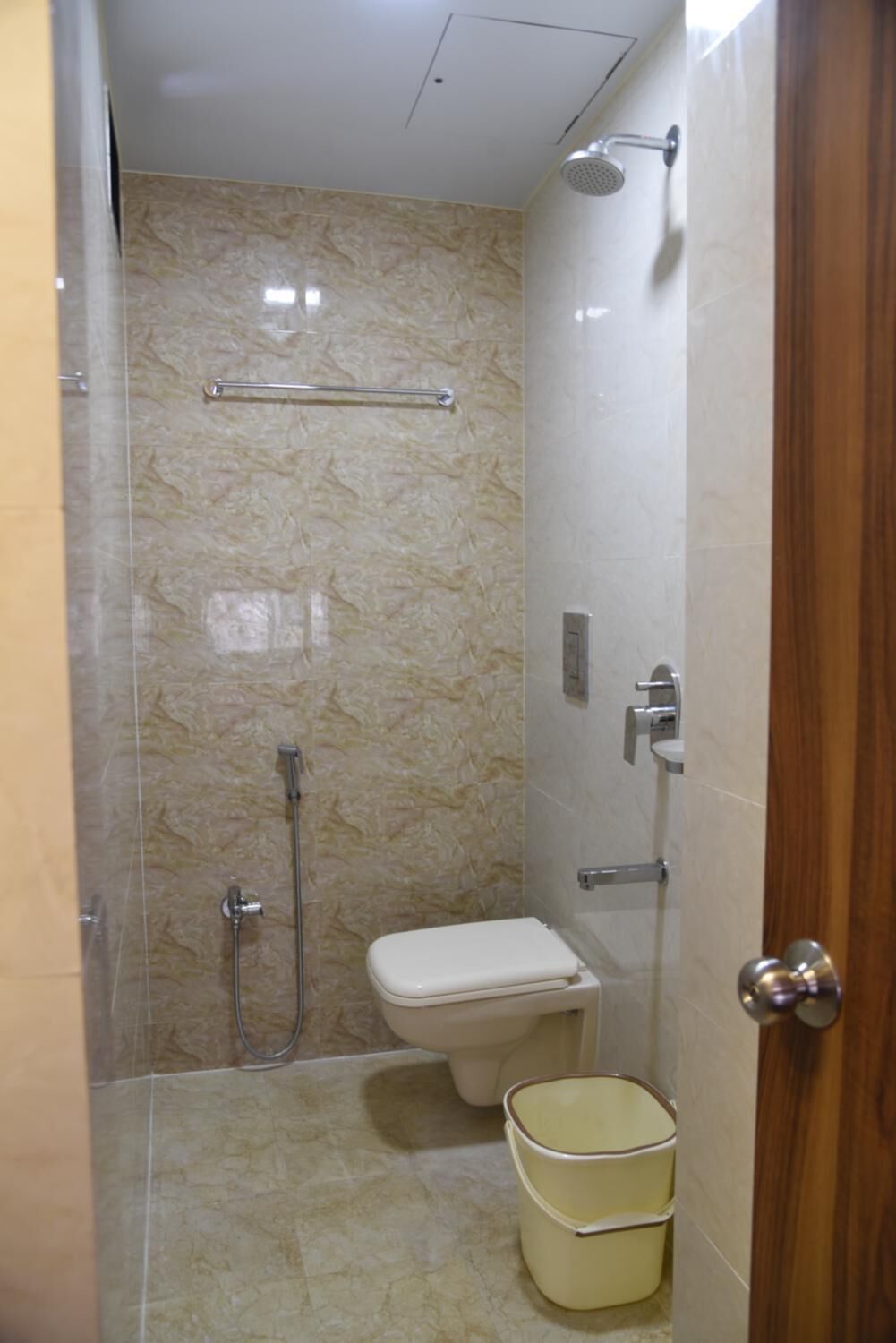 A small, enclosed bathroom with a toilet, a shower, and a hand basin.