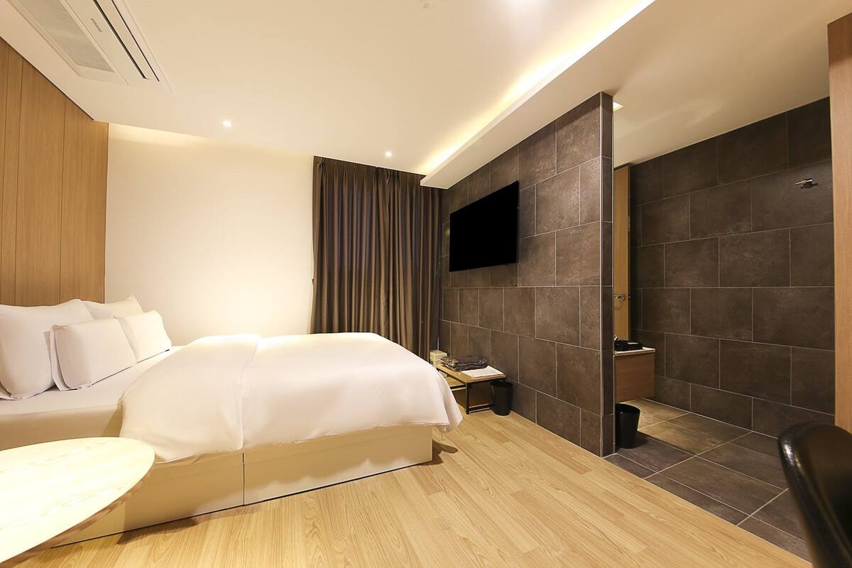 A modern hotel room with a bed, bedside table, and a TV mounted on the wall.