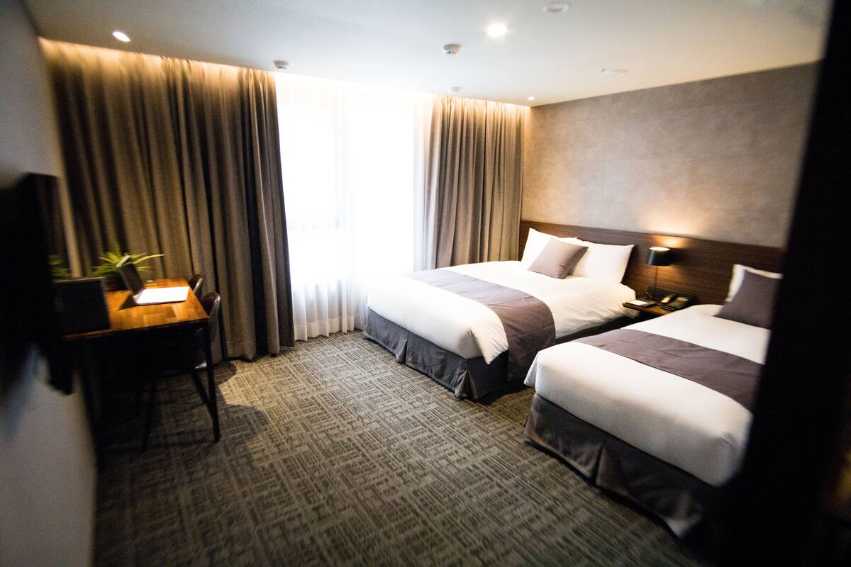 Une chambre d’hôtel avec deux lits, un bureau et une chaise.