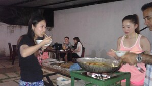 A group of people dining outdoors with a large wok on a table. - Kalan Villa (Galle)
