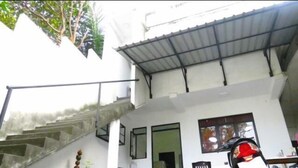 A two-story building with a staircase leading to the upper floor. There is a covered area with a metal roof, and a motorcycle parked outside. - Kalan Villa (Galle)