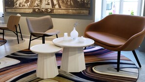 A modern interior with a round table, two chairs, a patterned rug, and a vintage cityscape painting on the wall. - Hotel St Josef (Zürich)