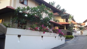 A residential building with a white exterior, a red-tiled roof, and a balcony with flowering plants. - 3-Bedroom Villa TG11 on Beachfront Resort SDV280-By Samui Dream Villas (Koh Samui)