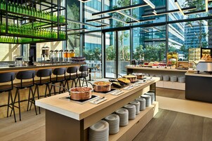 A modern breakfast bar with seating, a variety of food options, and a view of the cityscape.