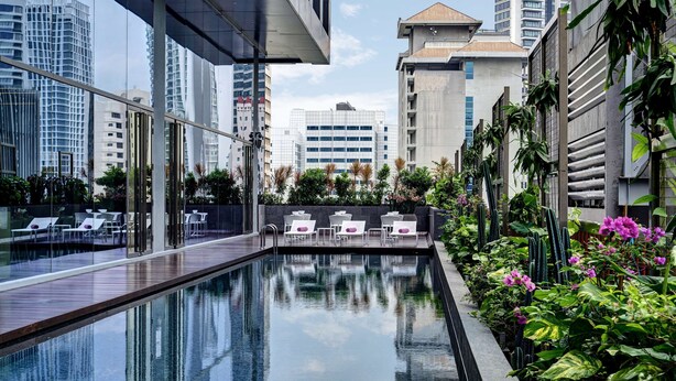 A rooftop pool area with lounge chairs, a clear view of surrounding buildings, and a variety of plants. - YOTEL Singapore Orchard Road (Singapore)