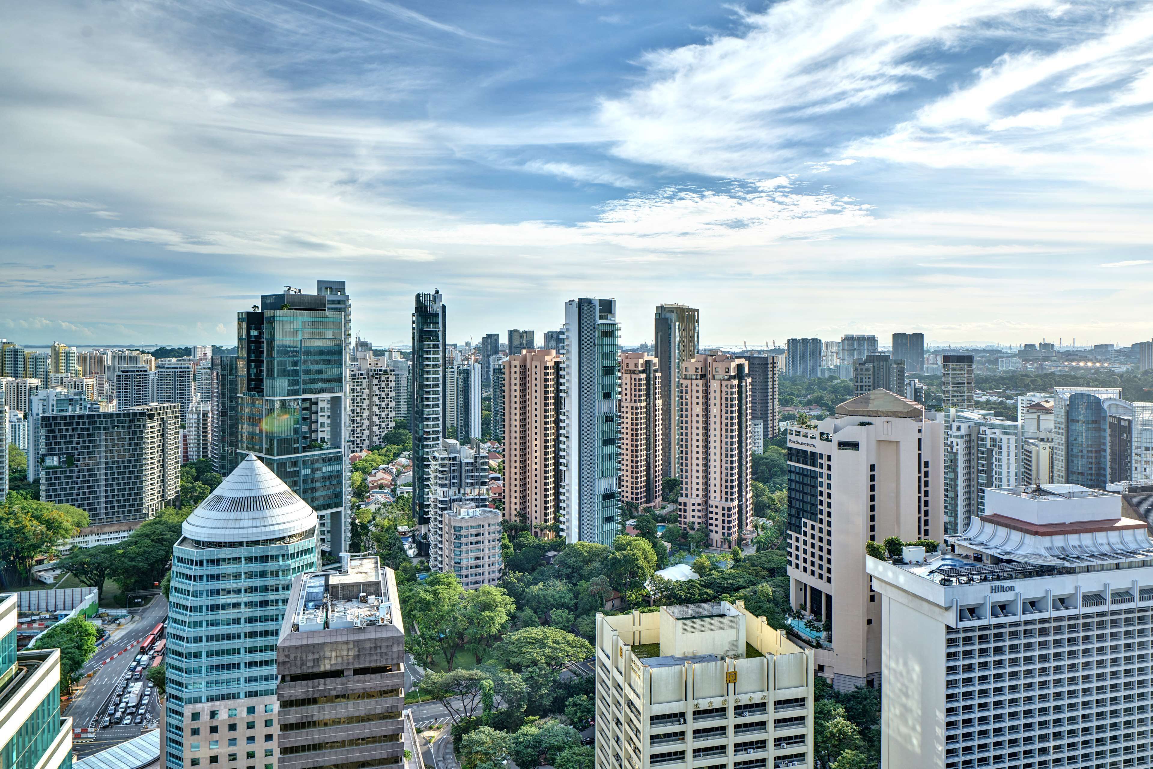 A high-rise hotel with multiple floors, surrounded by other tall buildings and greenery.