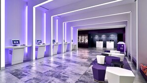 A modern hotel lobby with a long reception desk, individual workstations, and a seating area. - YOTEL Singapore Orchard Road (Singapore)