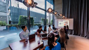 A modern conference room with large windows, a presentation screen, and a group of people engaged in a meeting.
