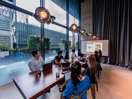 A modern conference room with large windows, a presentation screen, and a group of people engaged in a meeting.