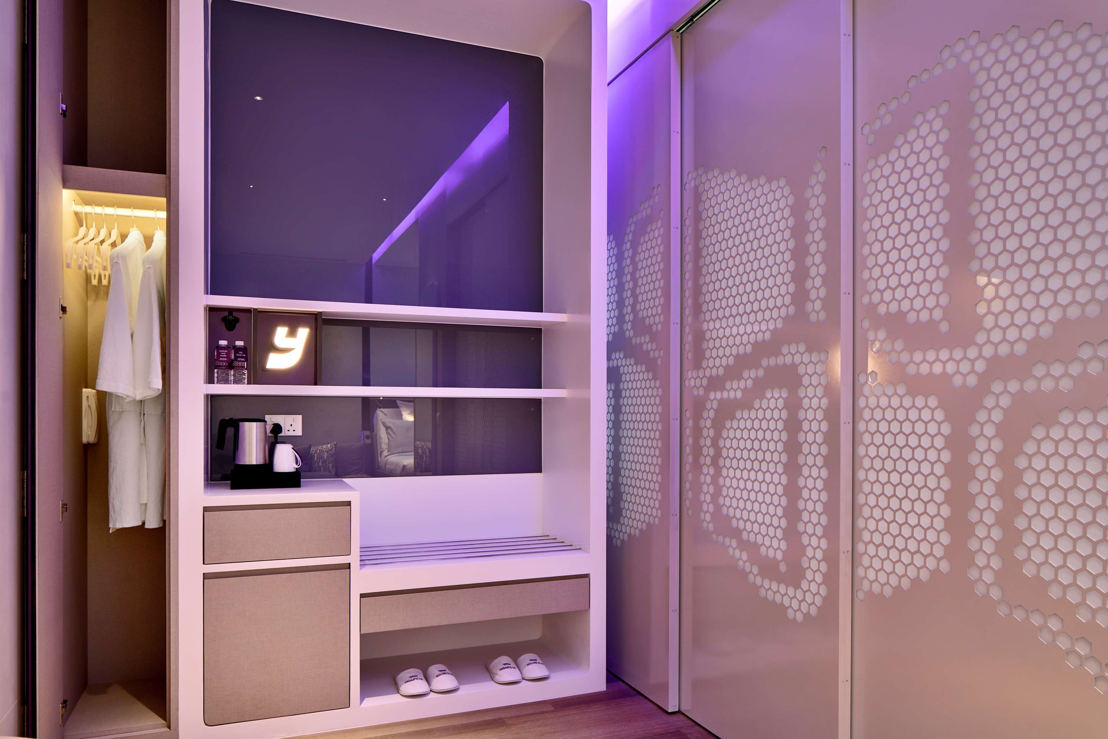 A modern room with a built-in TV, a coffee machine, and a shoe rack.