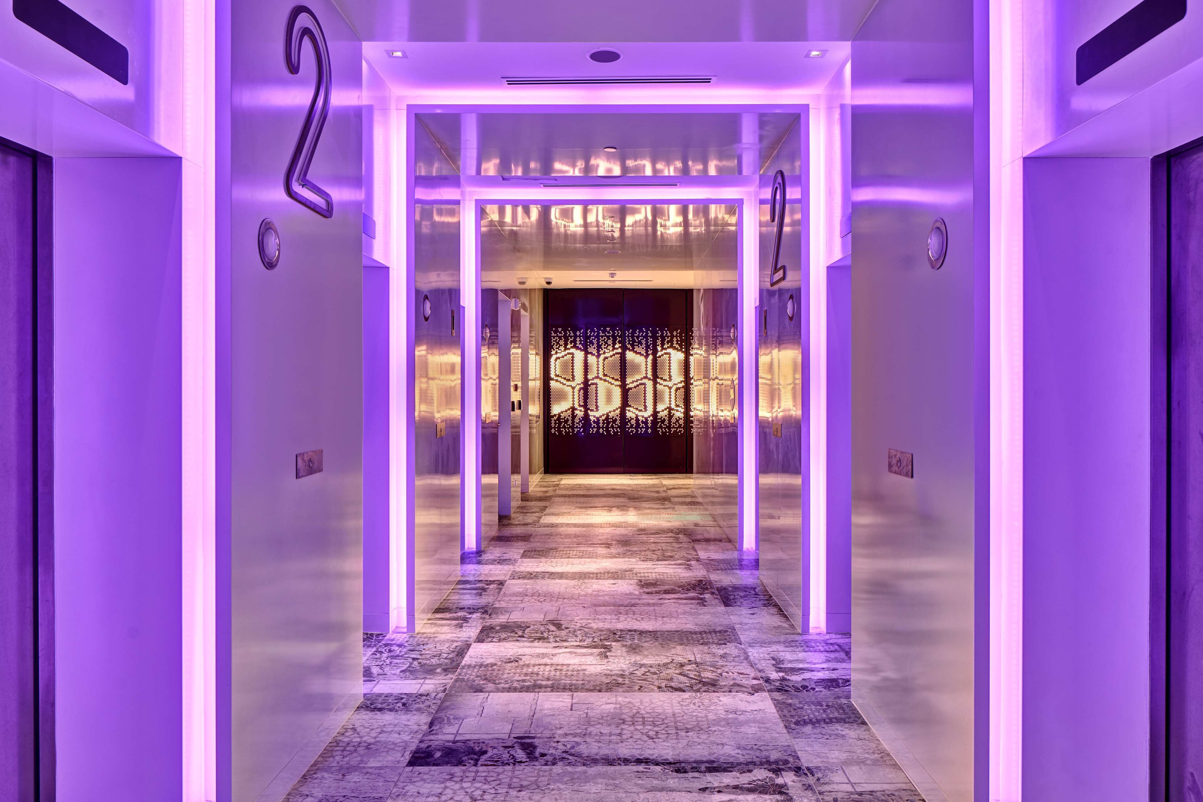 A hallway with a checkered floor and purple lighting.