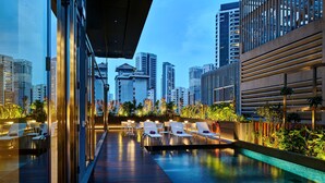 A rooftop pool area with lounge chairs and a view of surrounding high-rise buildings. - YOTEL Singapore Orchard Road (Singapore)