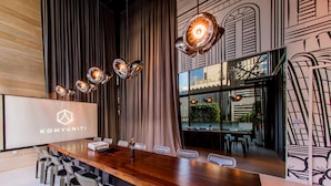 A conference room with a long wooden table, modern chairs, and a large screen displaying the logo "KOMYUNITI". - YOTEL Singapore Orchard Road (Singapore)