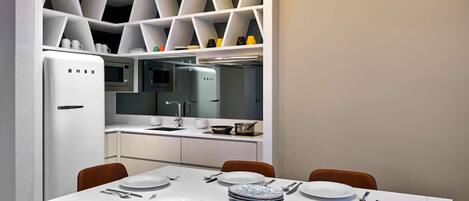 Un comedor moderno con una mesa blanca dispuesta para cuatro personas, rodeada de sillas naranjas.